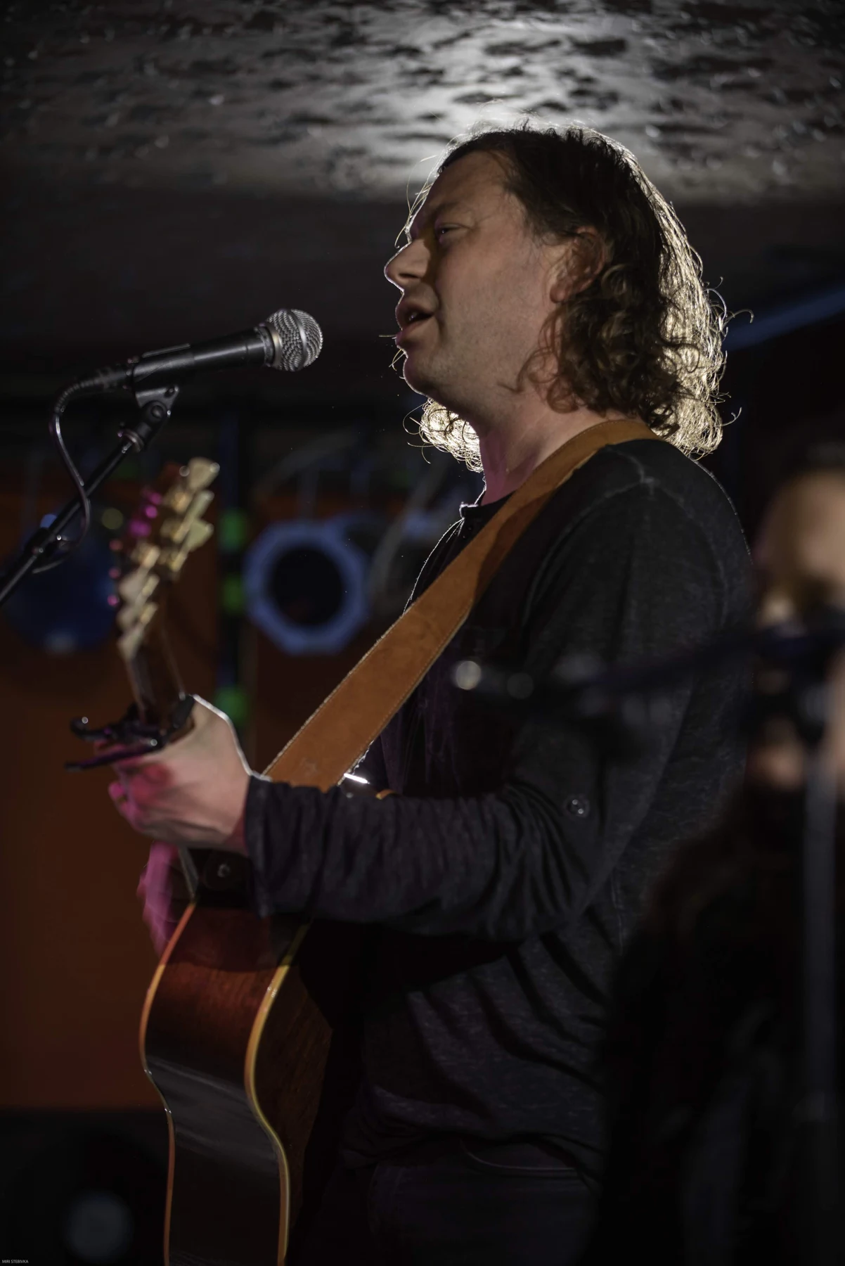 Brian singing and playing acoustic guitar onstage